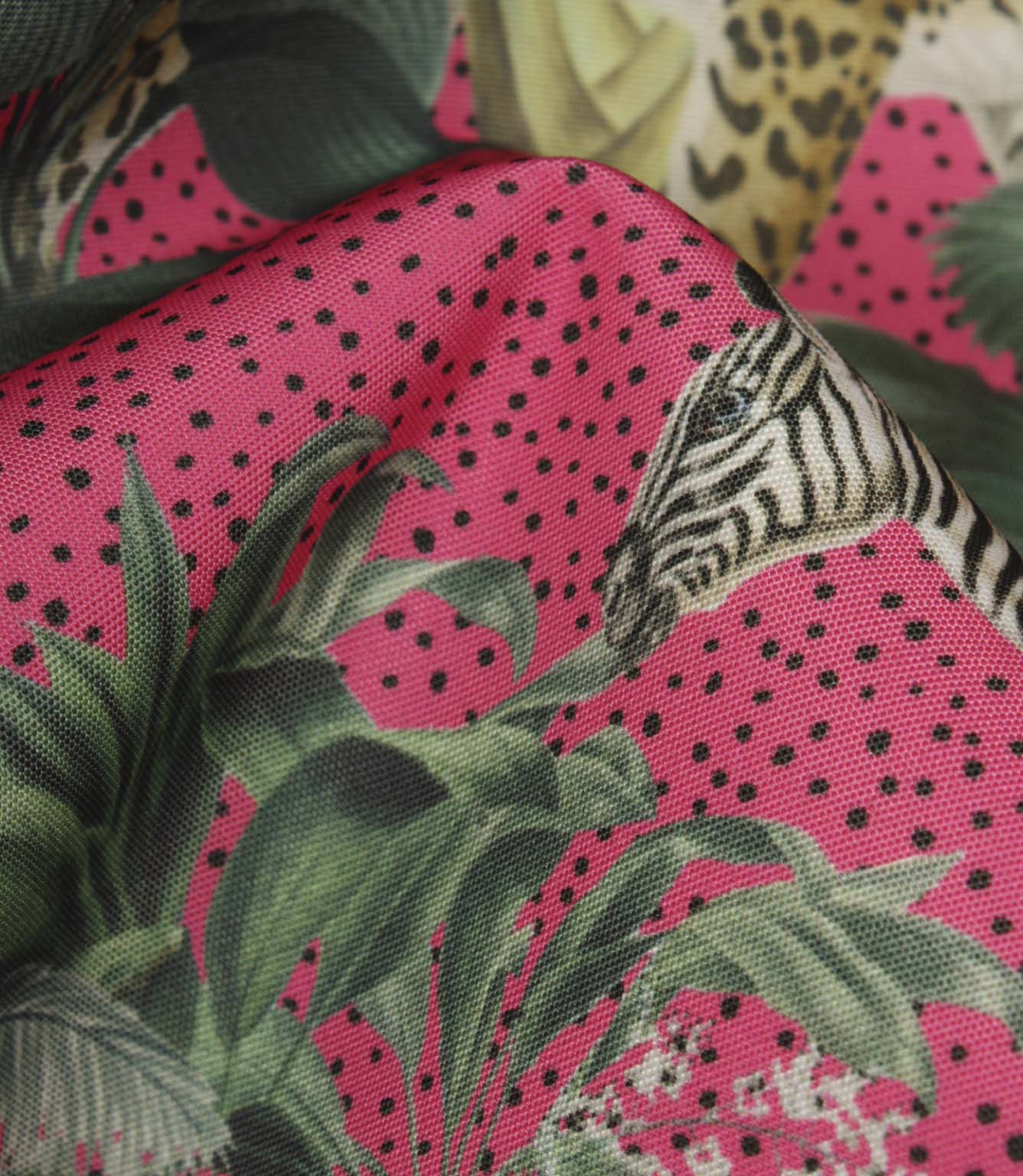 Close-up of tropical jungle fabric highlighting the textured weave, vivid pink background, black speckled detailing and exotic botanical print.