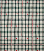 Cotswold Heart Tartan fabric in ivory and dark green, featuring a classic checked design with small red hearts and decorative red and white woven lines.