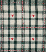 Close-up of Cotswold Heart Tartan ivory and green fabric, showing the woven check pattern, repeating red heart motifs and contrasting decorative thread detail.