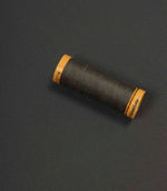 Charcoal grey fabric with a coordinating thread spool placed on top for colour comparison.