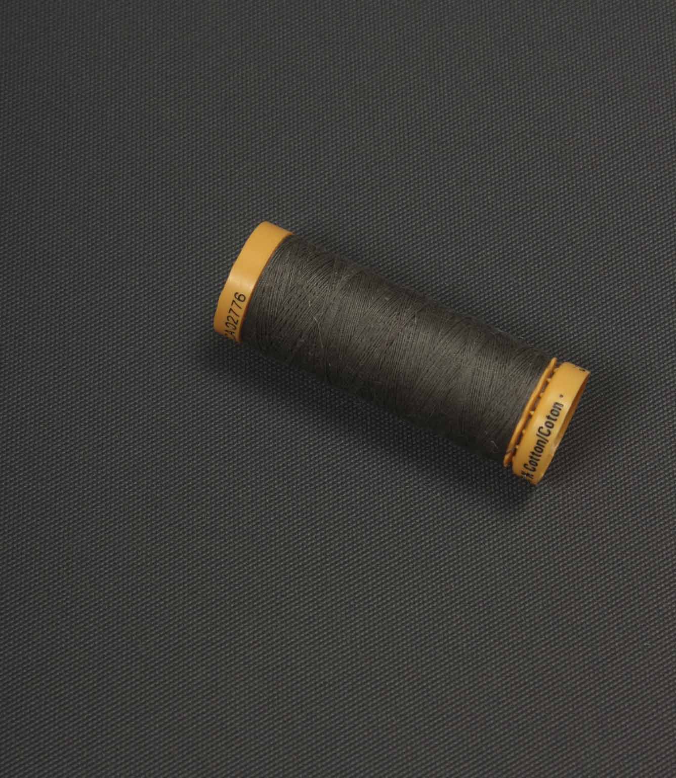 Charcoal grey fabric with a coordinating thread spool placed on top for colour comparison.