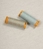 Grey fabric with coordinating Gütermann thread spools in neutral and pale blue for colour matching.