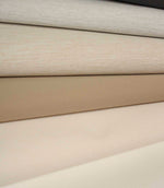 Folded fabric in soft neutral shades including cream, beige and taupe, with a fine, even woven texture.