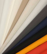 Fan arrangement of plain fabrics ranging from light neutrals through grey and navy to mustard and red.