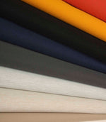 Stacked plain fabrics in cream, stone, grey and navy, highlighting subtle texture and tonal variation.