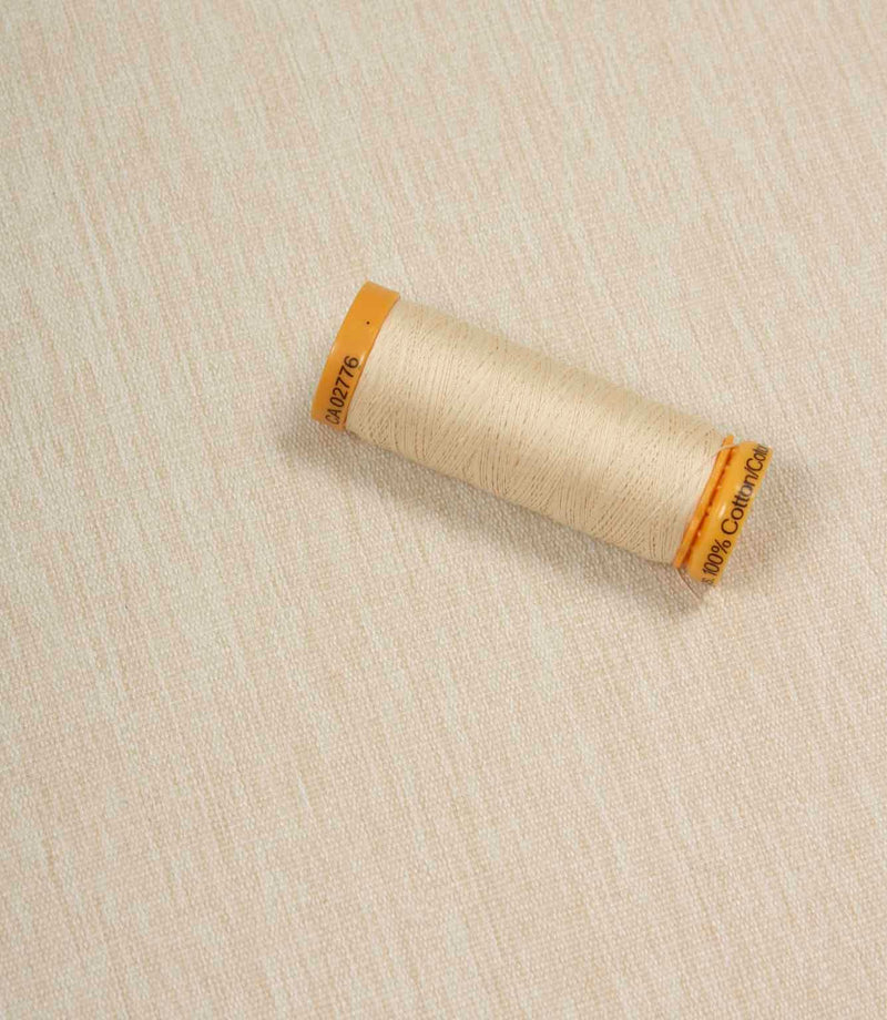 Beige fabric with a matching Gütermann thread spool placed on top for colour comparison.