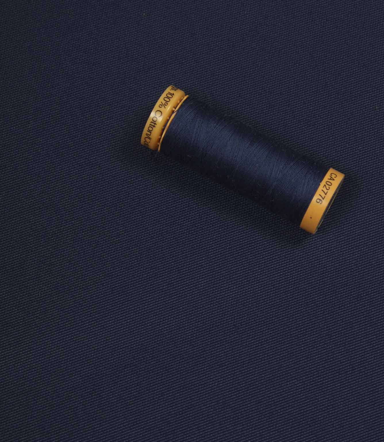 Navy blue fabric with a matching Gütermann thread spool placed on top for colour comparison.