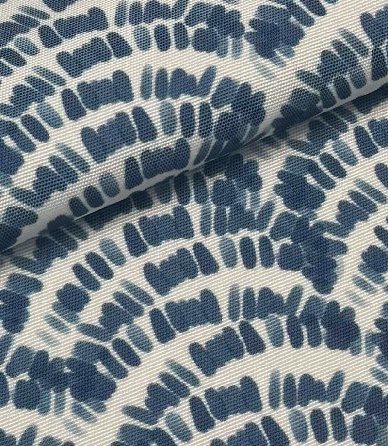 Folded coastal outdoor fabric with indigo blue abstract wave pattern on a soft ivory background.
