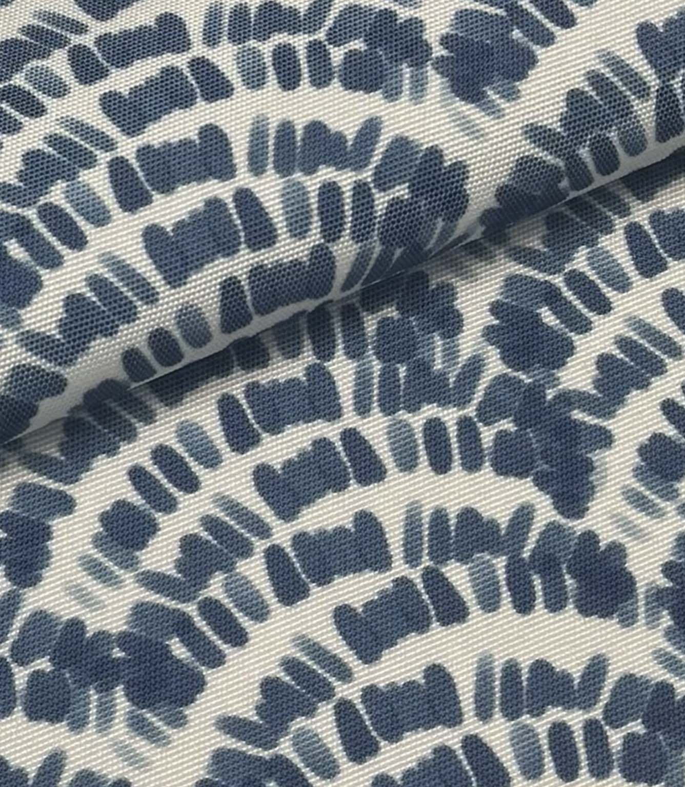 Folded coastal outdoor fabric with indigo blue abstract wave pattern on a soft ivory background.