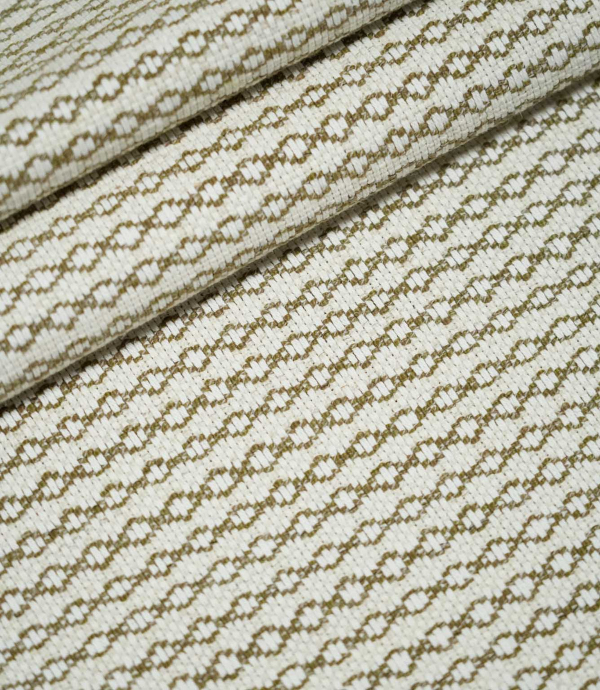 Elkstone Matcha woven fabric arranged in soft, overlapping folds, displaying its repeating olive green geometric pattern and textured cream surface.
