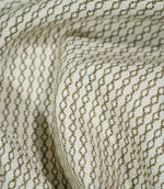 Elkstone Matcha fabric loosely gathered into deep folds, showing the continuous olive green geometric pattern woven into a textured natural cream background.