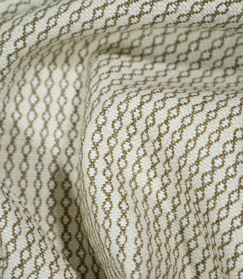 Elkstone Matcha fabric loosely gathered into deep folds, showing the continuous olive green geometric pattern woven into a textured natural cream background.
