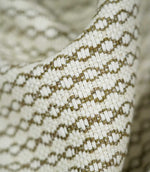 Extreme close-up of Elkstone Matcha upholstery fabric revealing its interwoven cream and olive green yarns, raised surface texture and repeating small-scale geometric motifs.