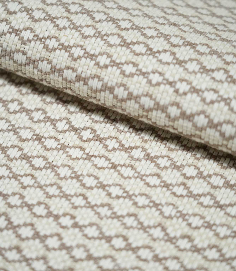 Close-up of folded Elkstone Taupe fabric showing its chunky woven texture, raised cream yarns and repeating taupe geometric motifs.