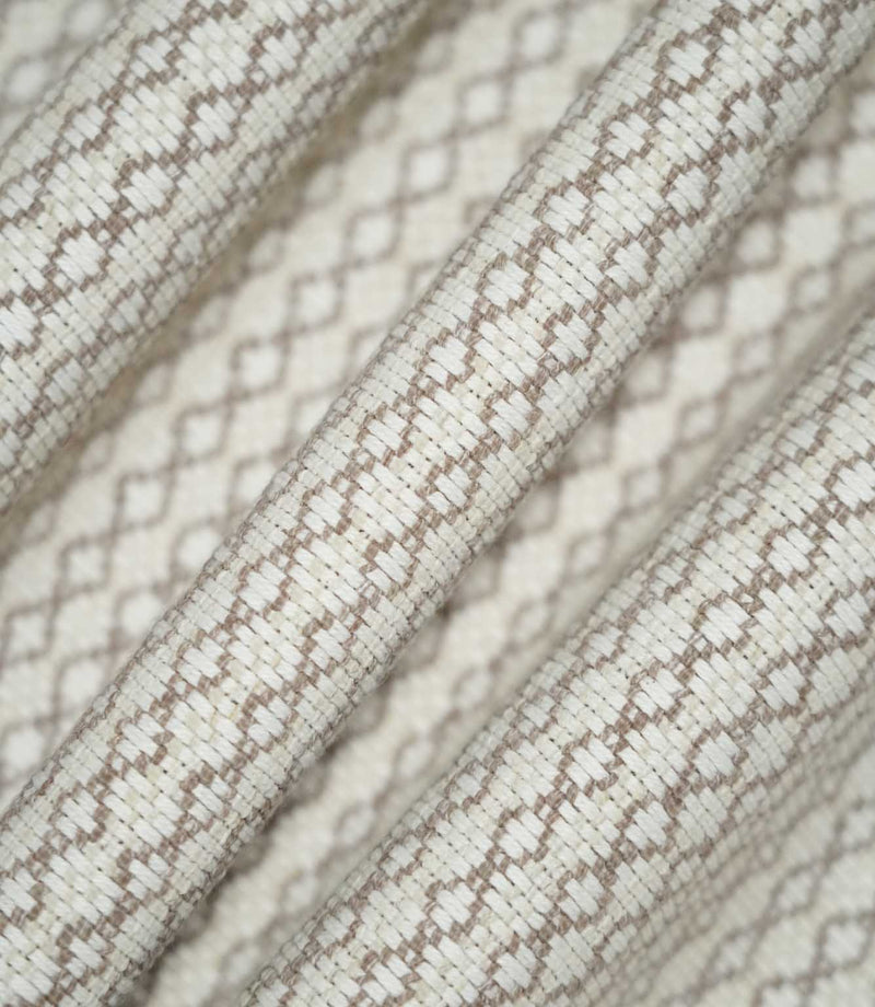 Detailed view of Elkstone Taupe fabric gathered into soft folds, highlighting its tactile woven texture and small-scale geometric design in taupe and cream.