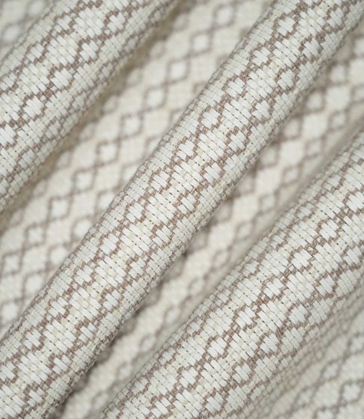 Detailed view of Elkstone Taupe fabric gathered into soft folds, highlighting its tactile woven texture and small-scale geometric design in taupe and cream.