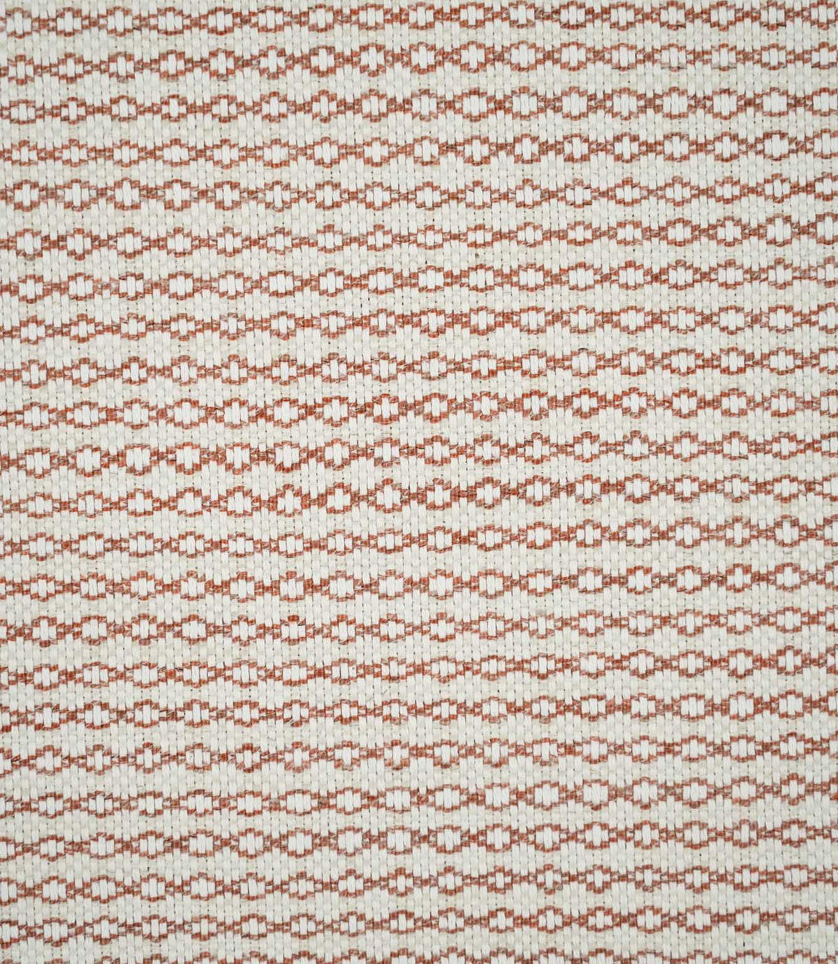 Full view of Elkstone Terracotta woven fabric showing a small-scale geometric pattern of repeating rust-orange linked shapes across a natural cream background.