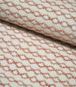 Close-up of folded Elkstone Terracotta fabric showing its structured woven texture, raised cream yarns and small-scale terracotta geometric motifs.