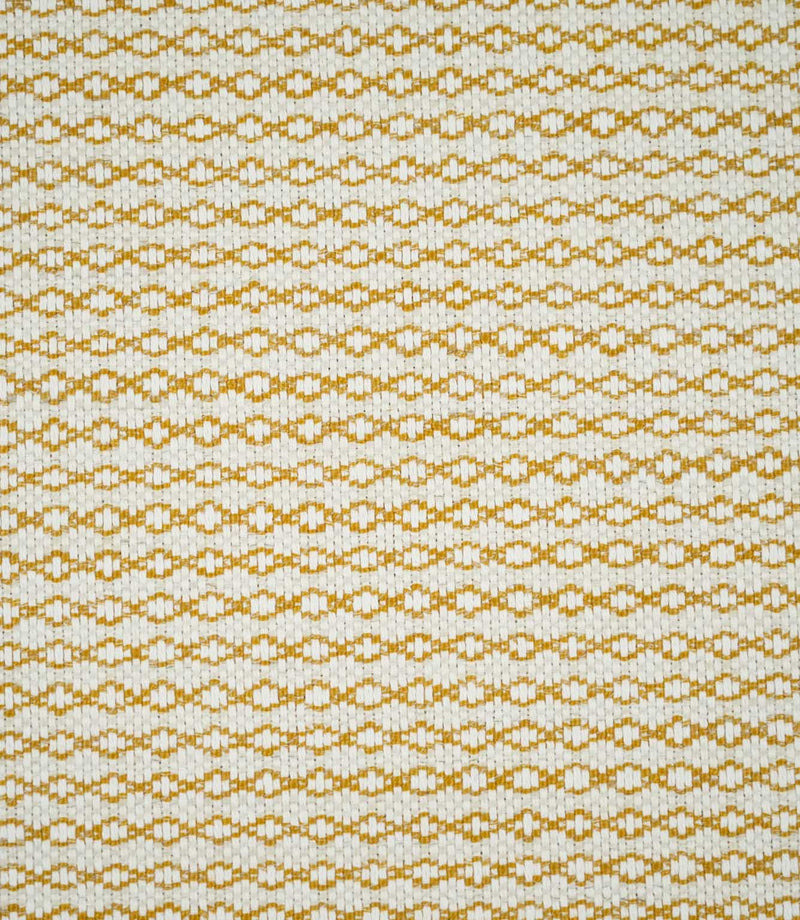 Full view of Elkstone Turmeric woven fabric showing a small-scale geometric pattern of interlocking golden yellow shapes across a natural cream background.