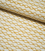 Close-up of folded Elkstone Turmeric fabric showing its chunky woven texture, raised cream yarns and repeating mustard yellow geometric motifs.