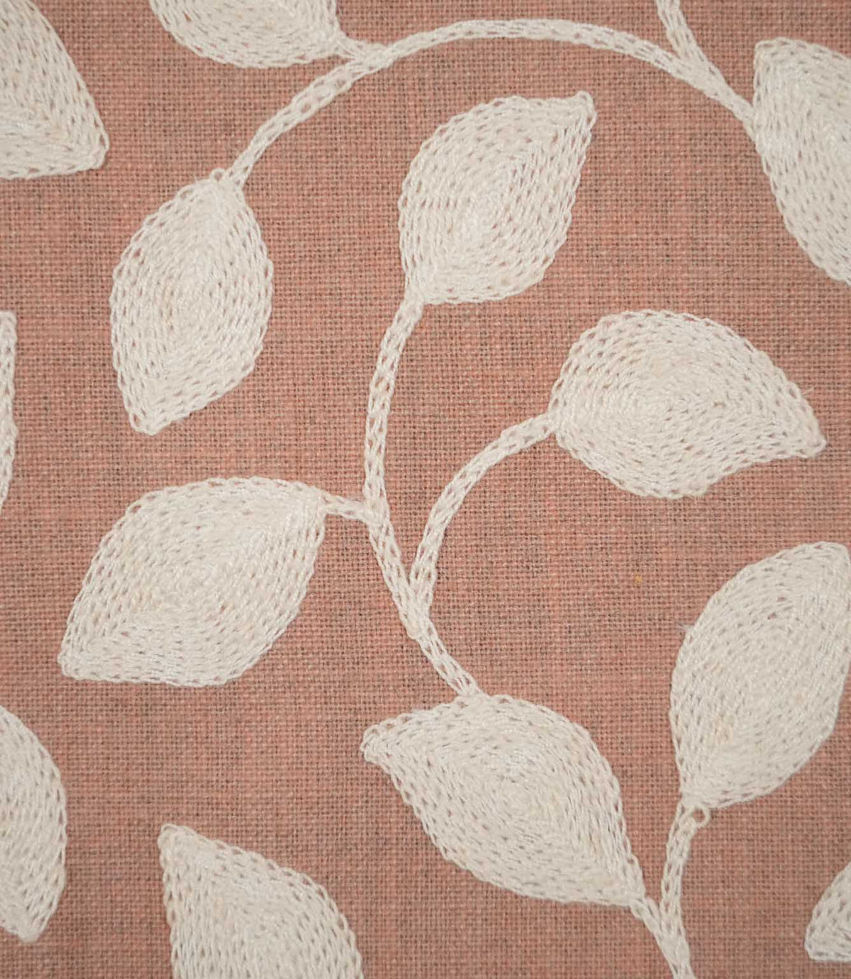 Detailed close-up of Ellerton Blush fabric showing raised cream embroidered leaves and delicate winding stems against a blush pink woven ground, highlighting the individual stitches, subtle fabric weave and tactile texture of the botanical design.