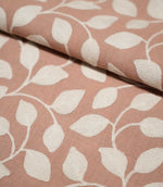 Close-up of folded Ellerton Blush fabric showing the cream embroidered leaf and trailing vine pattern continuing across a blush pink woven ground, with the fold demonstrating the fabric's structure, thickness and softly textured finish.