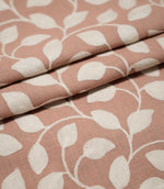 Ellerton Blush embroidered fabric arranged in overlapping folds, featuring raised cream botanical leaves connected by flowing curved stems on a blush pink woven background, highlighting the repeating foliage pattern, detailed stitching and natural movement of the fabric.