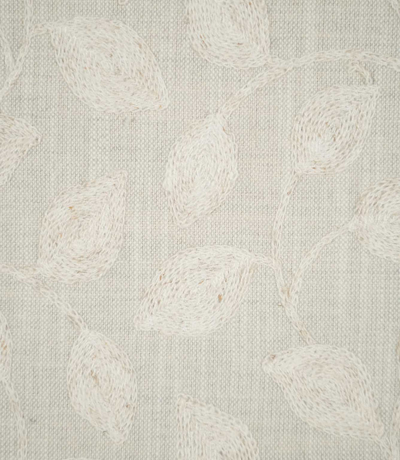 Detailed close-up of Ellerton Cloud fabric showing raised ivory embroidered leaves connected by slender, curving stems on a pale cloud-grey woven ground, highlighting the individual stitches, softly textured weave and tactile finish of the botanical embroidery.