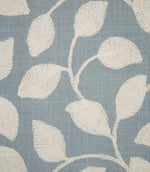 Detailed close-up of Ellerton Cornflower fabric showing raised cream leaf embroidery and delicate stitched stems against a textured cornflower blue woven ground, highlighting the individual threads and tactile finish of the contemporary foliage design.