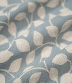 Ellerton Cornflower embroidered fabric arranged in gentle flowing folds, with cream foliage embroidery sweeping across the cornflower blue woven ground, showing the botanical pattern, textured stitching and soft drape suitable for curtains, blinds, cushions and decorative upholstery.
