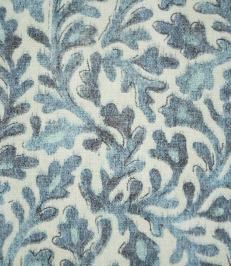 Close-up of Elmsley blue fabric showing the detailed floral and foliage print in layered blue, aqua and navy shades against a cream background.