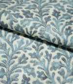 Folded Elmsley blue fabric showing the small-scale botanical pattern and woven surface texture, with blue and aqua foliage on a soft cream ground.