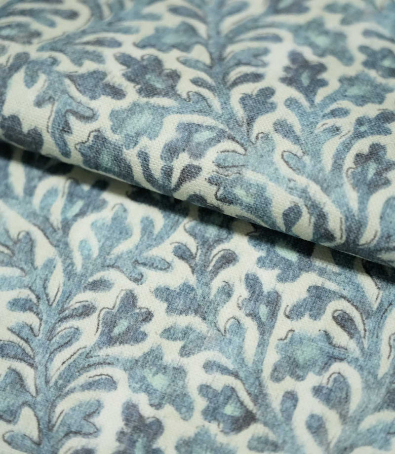 Folded Elmsley blue fabric showing the small-scale botanical pattern and woven surface texture, with blue and aqua foliage on a soft cream ground.
