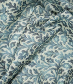 Elmsley blue fabric loosely draped into soft folds, showing how the small-scale floral and foliage pattern looks when gathered for curtains, blinds or soft furnishings.