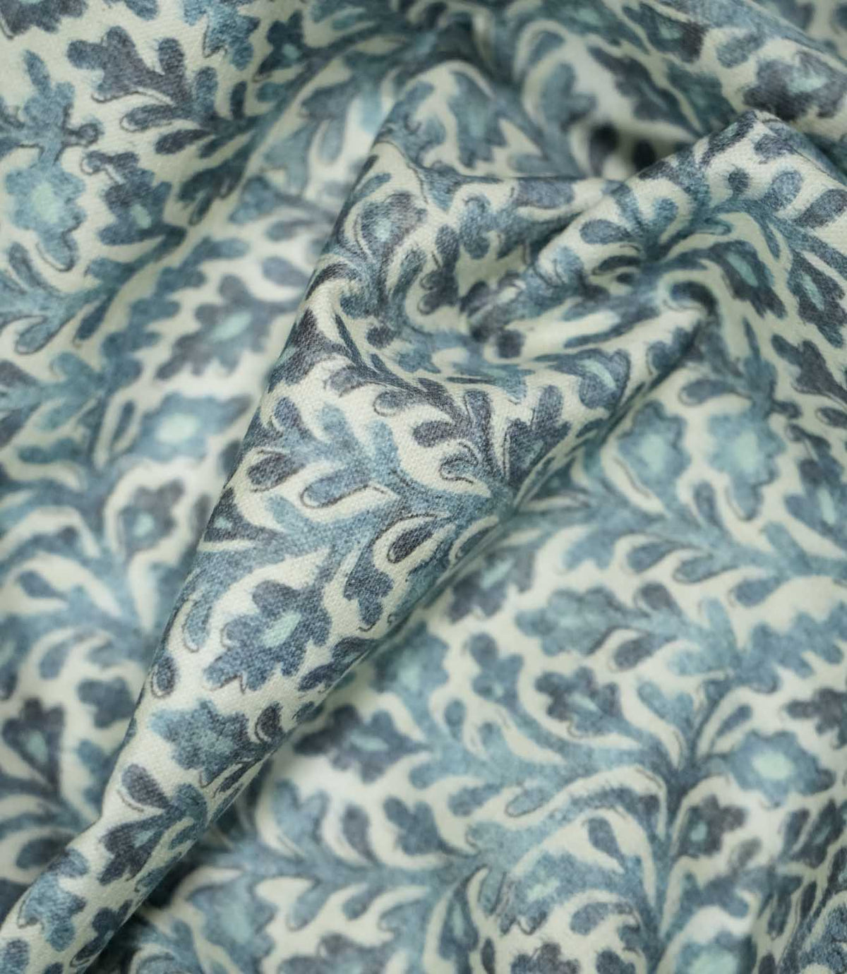 Elmsley blue fabric loosely draped into soft folds, showing how the small-scale floral and foliage pattern looks when gathered for curtains, blinds or soft furnishings.
