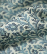 Macro close-up of draped Elmsley blue fabric highlighting the woven texture and botanical print in soft blue, aqua and navy tones on a cream ground.