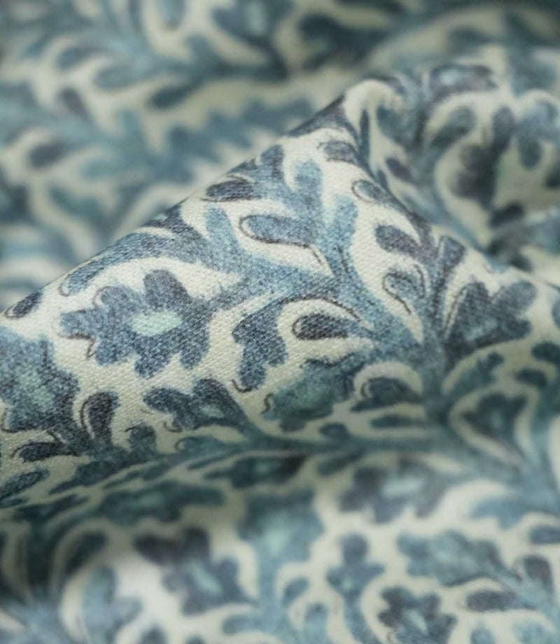 Macro close-up of draped Elmsley blue fabric highlighting the woven texture and botanical print in soft blue, aqua and navy tones on a cream ground.