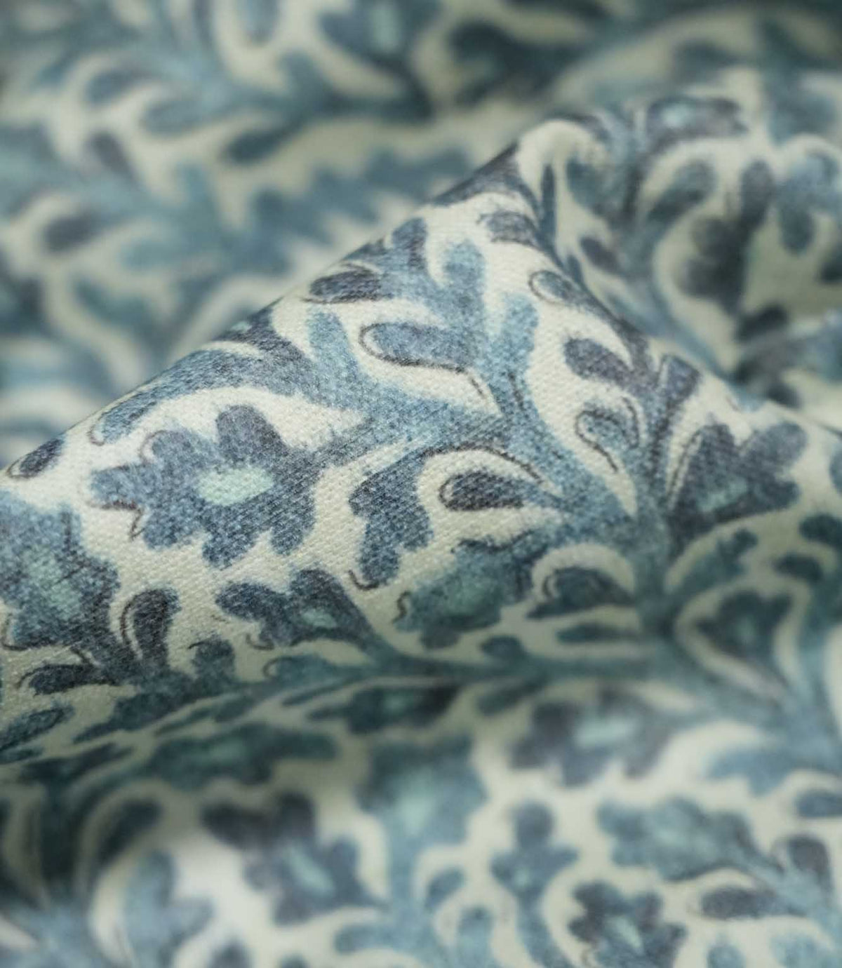 Macro close-up of draped Elmsley blue fabric highlighting the woven texture and botanical print in soft blue, aqua and navy tones on a cream ground.