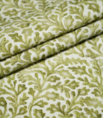 Elmsley Green fabric arranged in layered folds, highlighting the repeating small-scale floral and foliage print, natural woven texture and tonal olive and moss green botanical details on an off-white ground.