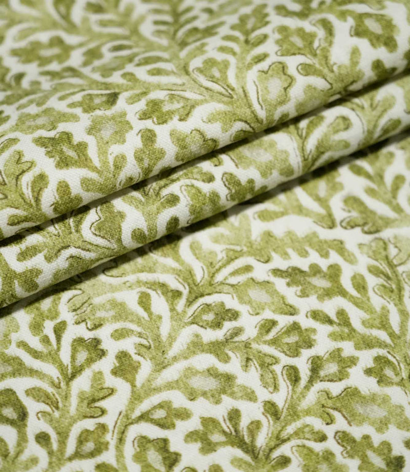 Elmsley Green fabric arranged in layered folds, highlighting the repeating small-scale floral and foliage print, natural woven texture and tonal olive and moss green botanical details on an off-white ground.