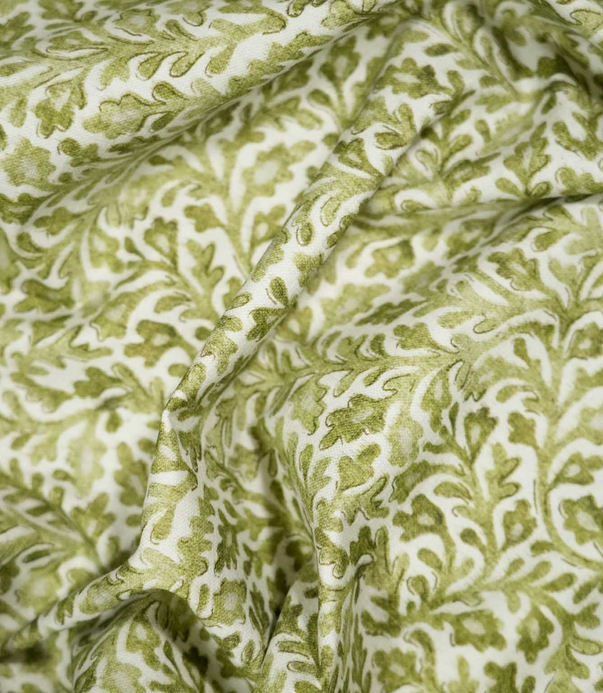 Elmsley Green sustainable fabric loosely draped into soft flowing folds, showing how the small-scale green floral and foliage pattern falls naturally when used for curtains, Roman blinds, cushions or soft furnishings.