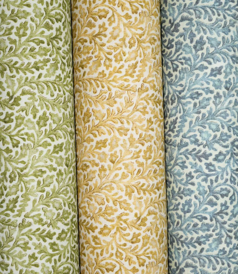 Three Elmsley floral fabrics displayed side by side in green, ochre and blue colourways, each featuring the same small-scale flowing foliage and stylised floral pattern on a soft off-white ground.