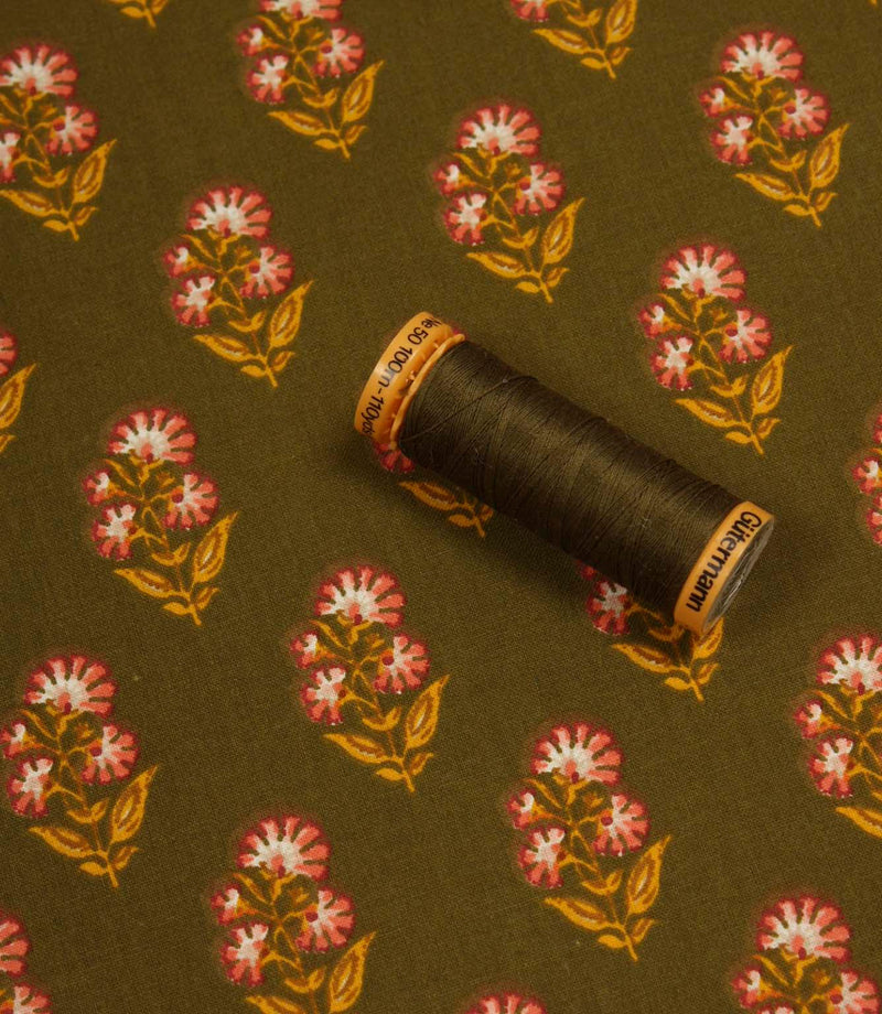 Olive floral print fabric displayed with a coordinating dark thread spool to highlight colour matching.