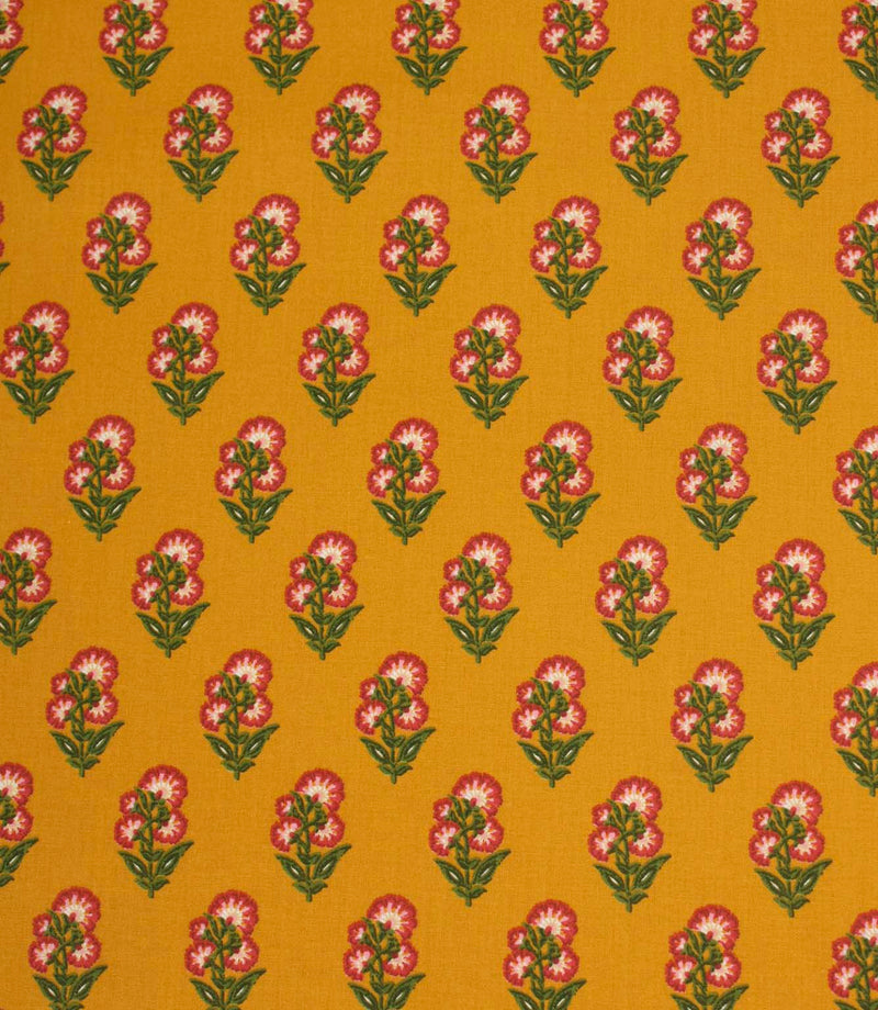 Mustard yellow fabric featuring a repeating floral sprig pattern with pink and white blooms and green foliage.
