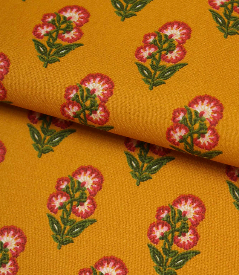 Mustard botanical print fabric folded to show the smooth texture and repeating floral design.