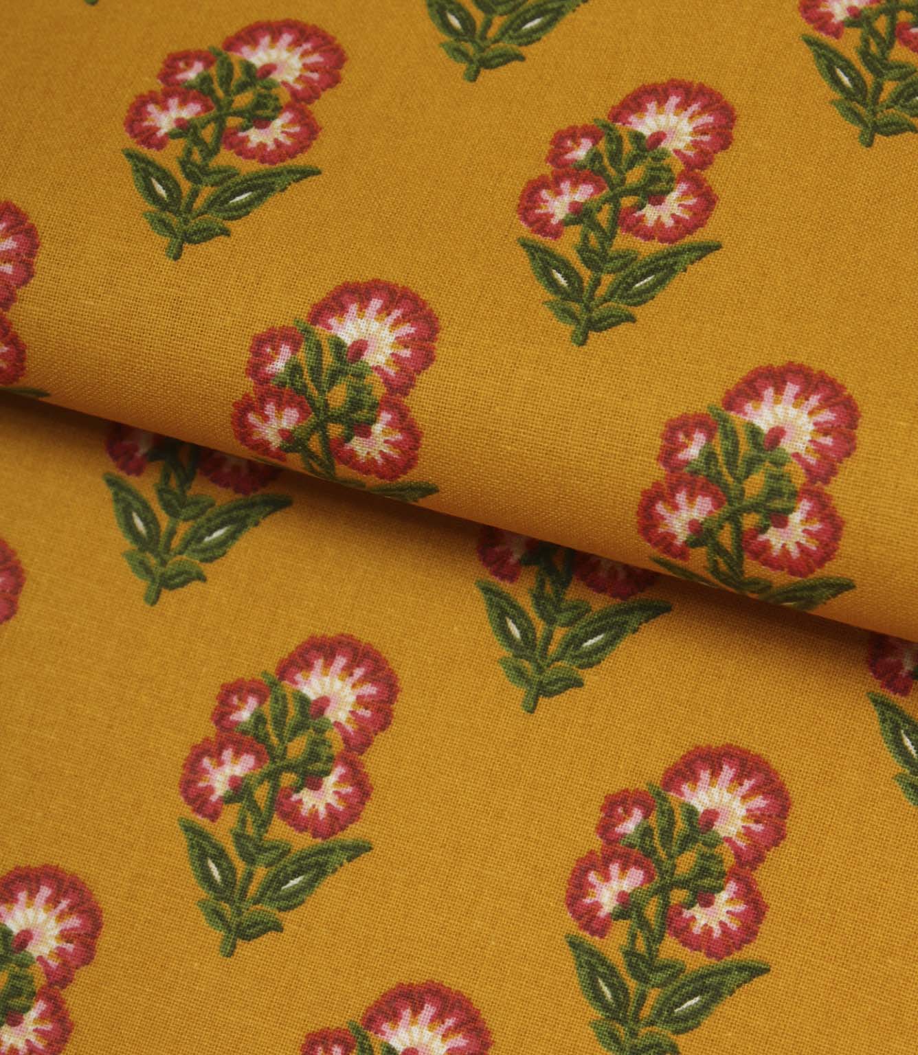 Mustard botanical print fabric folded to show the smooth texture and repeating floral design.