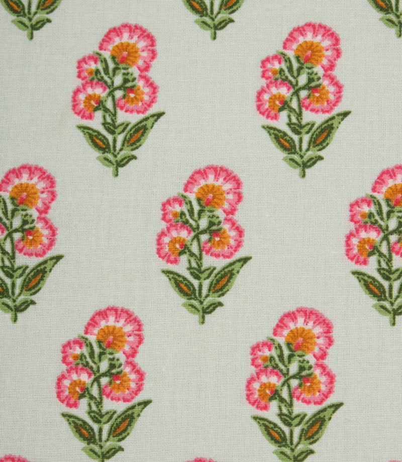 Close-up of ditsy floral fabric with stylised pink flowers and leafy green stems on a light neutral base.