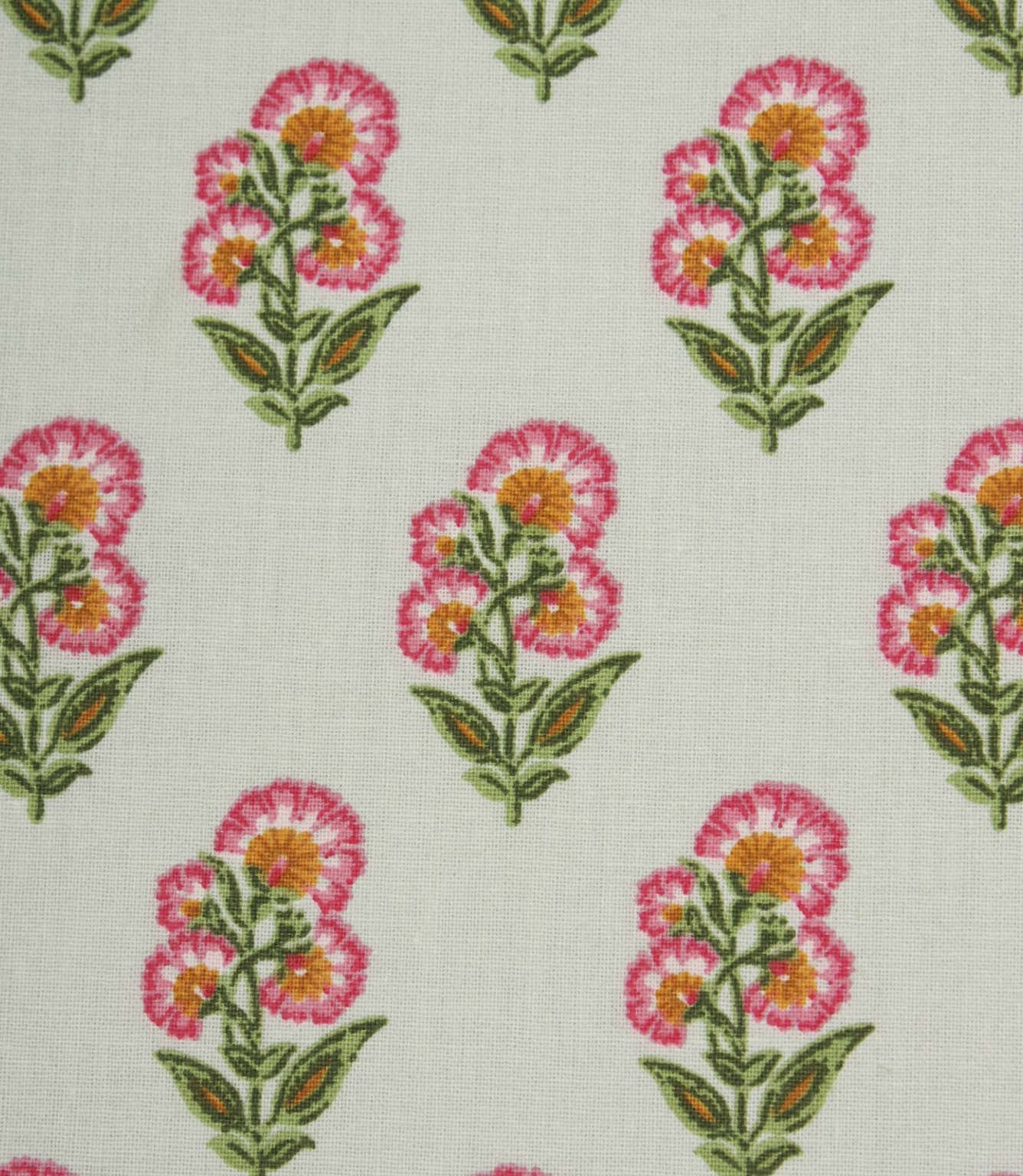 Close-up of ditsy floral fabric with stylised pink flowers and leafy green stems on a light neutral base.