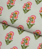 Folded floral print fabric with small-scale pink flowers and soft green leaves on a fresh light cream background.