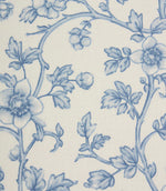 Close-up of blue botanical fabric showing intricate floral vines and fine illustrated detailing on a light neutral base.